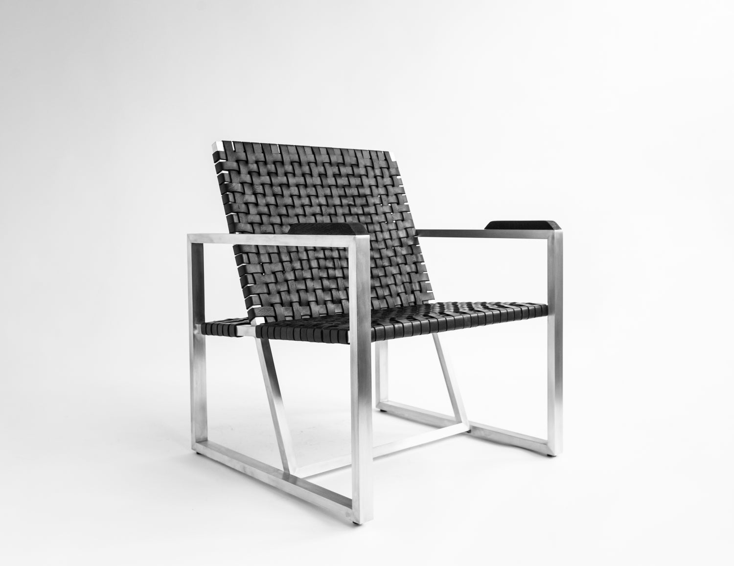 A contemporary lounge chair with a minimalist metal frame and black woven seating, designed for outdoor use.